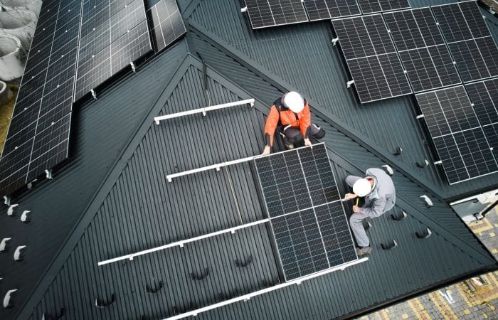 Workmen attaching solar panels to roof of a building