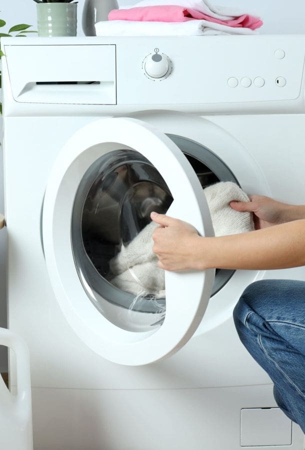 Lady putting dirty clothes into a washing machine