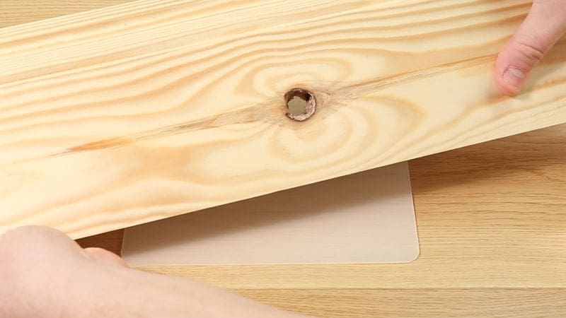 Large straight-through knot in a piece of wood with a silicone mat underneath it