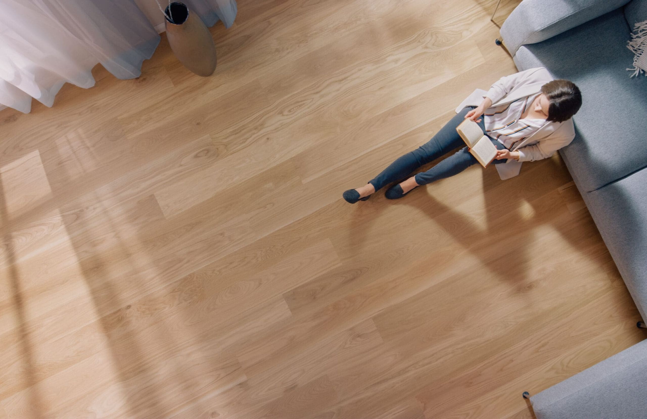 Young woman is sitting on a floor and reading a book