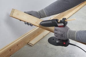 Glue gun being used to apply hot melt to an edge wood flooring piece