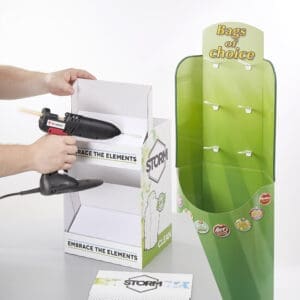Glue gun being used to apply hot glue to a point of sale display